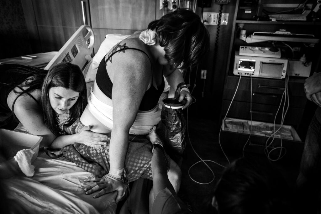 A doula doing the double hip squeeze at the bedside of a laboring person.