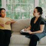 A doula and a client having a prenatal discussion on a couch