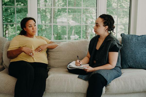 A doula and a client having a prenatal discussion on a couch