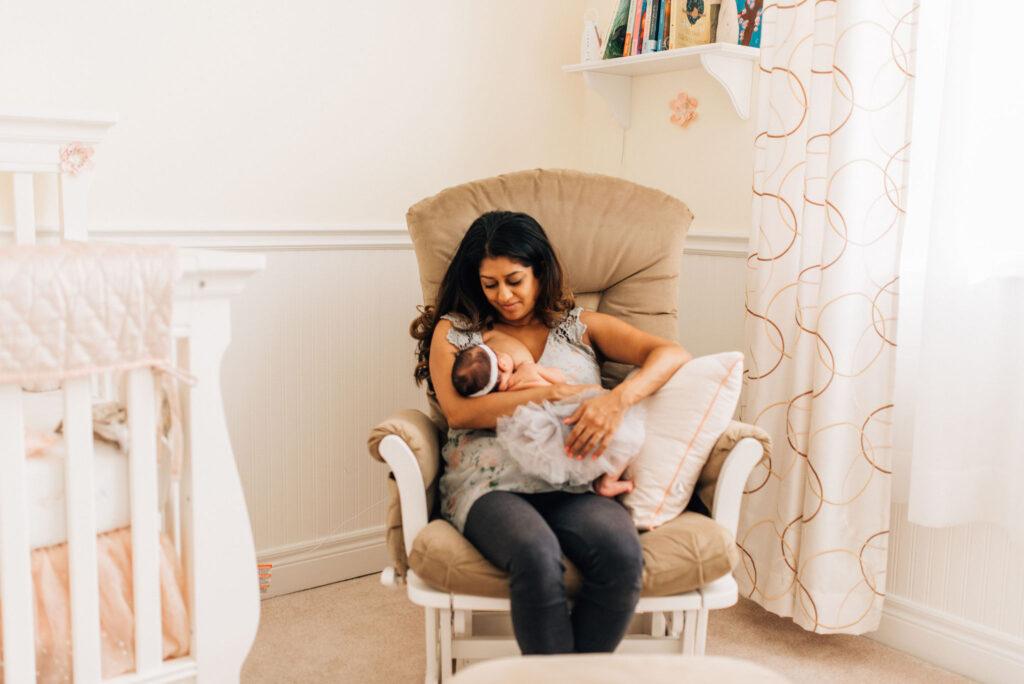 New mom sitting in a glider with a newborn breastfeeding.