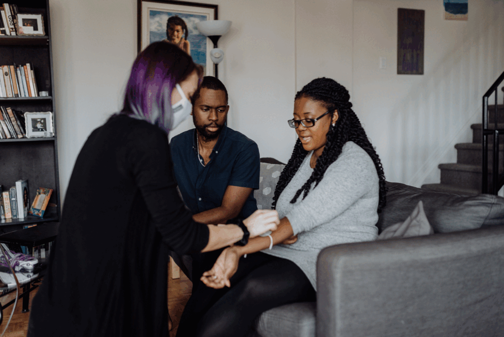 A doula shows a pregnant couple how to use TENS for their upcoming labor.