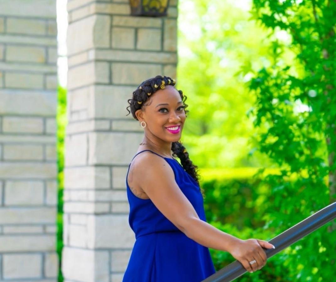 Doula Anihhya Trumbo wearing a blue dress near a green bush