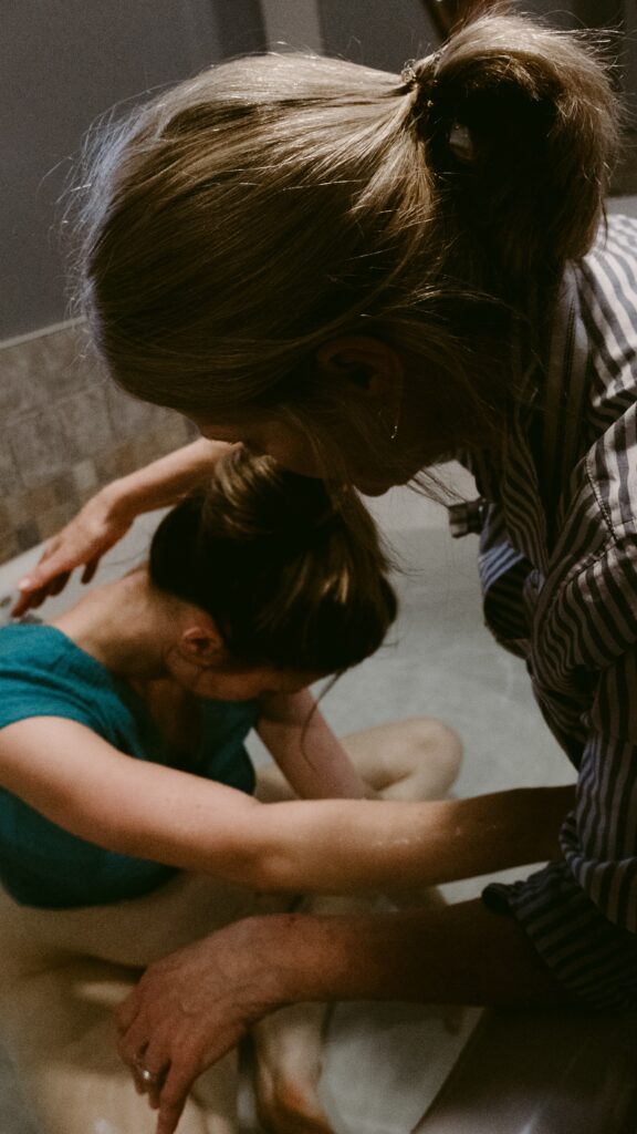 A birth doula comforting a laboring person in a tub