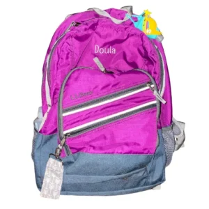 A magenta back pack with the word DOULA embroidered on it.