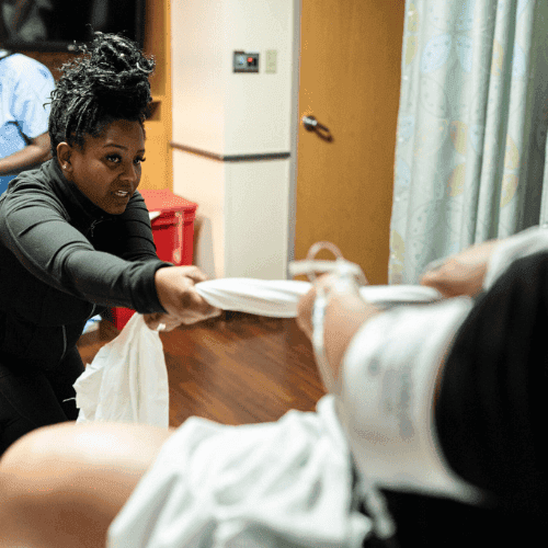 Diverse doula practicing support techniques during childbirth education class.