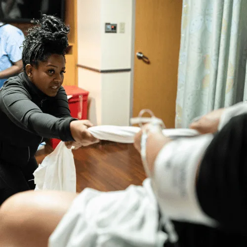 Diverse doula practicing support techniques during childbirth education class.