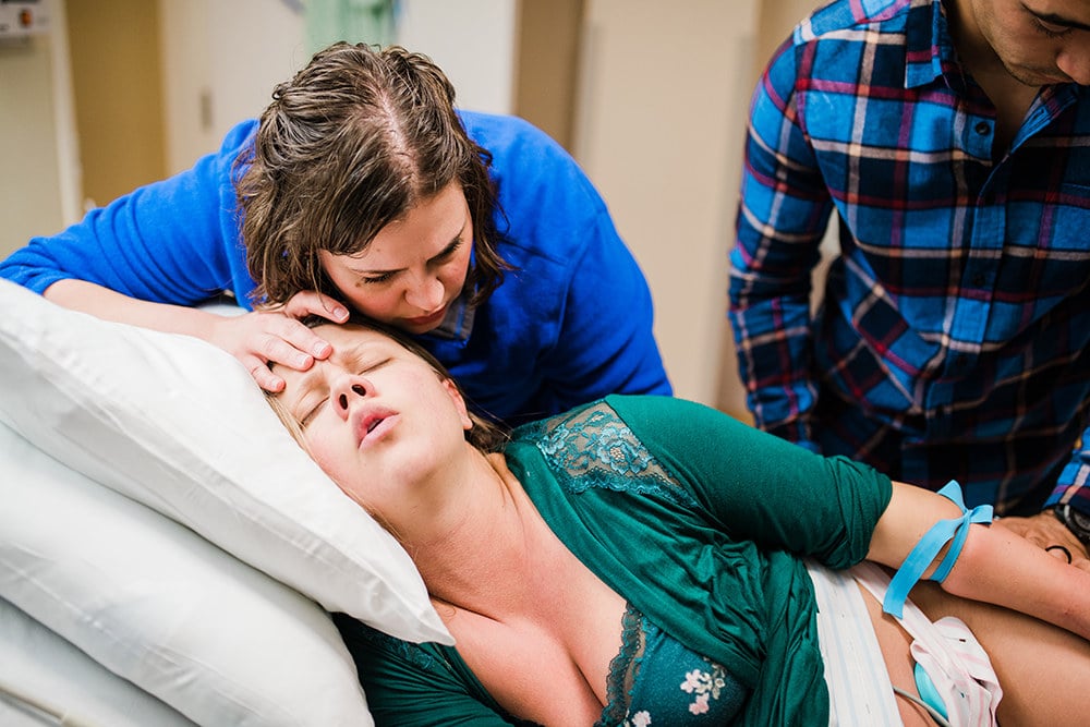 A doula massages someone during a labor contraction.