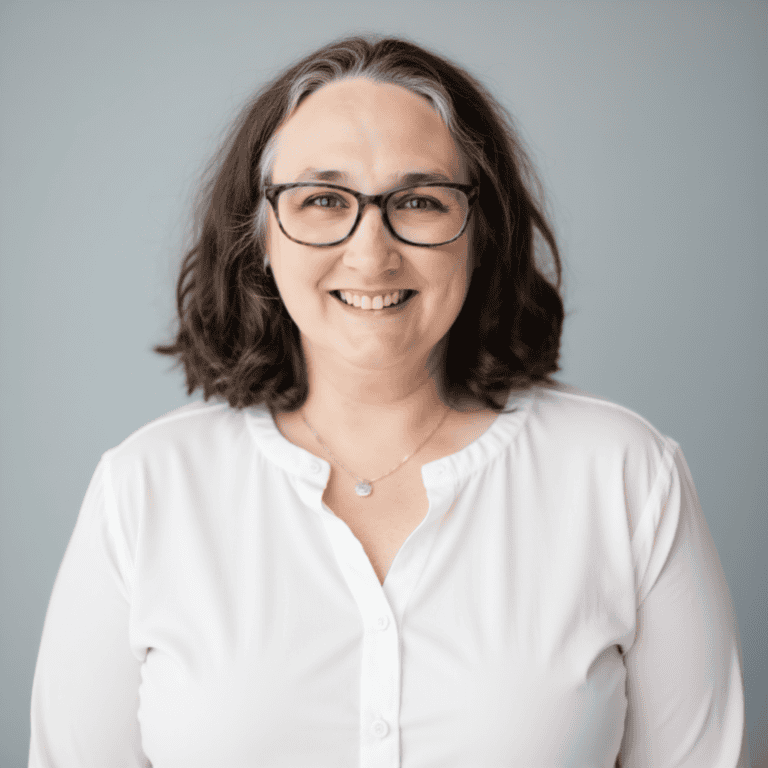 Friendly woman with glasses smiling for childbirth support classes.