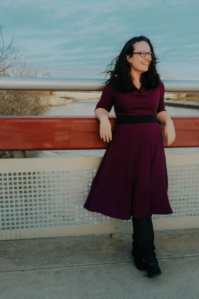 Woman smiling on bridge, exploring doula training opportunities.